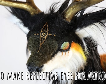 May include: A close-up of a fantasy art doll head with black, white, and orange fur. The doll has golden antlers and reflective eyes. The text "HOW TO MAKE REFLECTIVE EYES FOR ARTDOLLS" is at the bottom of the image.