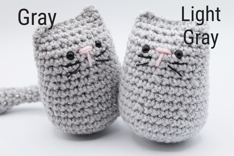 May include: Two crocheted cat toys, one gray and one light gray. Both have black eyes, pink noses, and black whiskers.