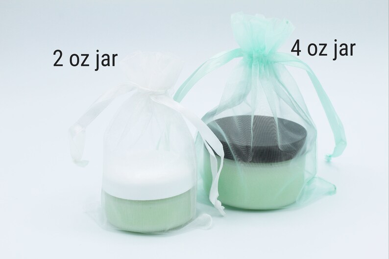 May include: Two jars of green cream in white and light green organza bags. The smaller jar is labelled "2 oz jar" and the larger jar is labelled "4 oz jar".