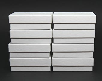 May include: A stack of ten white cardboard boxes, arranged in two columns of five boxes each.