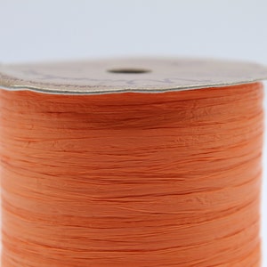 May include: A spool of orange paper ribbon. The ribbon is made of thin, crinkled paper strips.