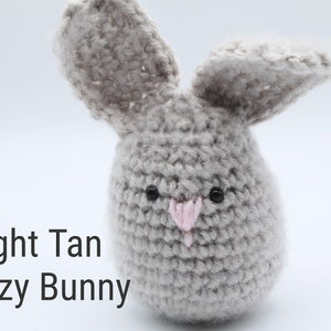 May include: A light tan fuzzy bunny crochet toy with black eyes and a pink nose.