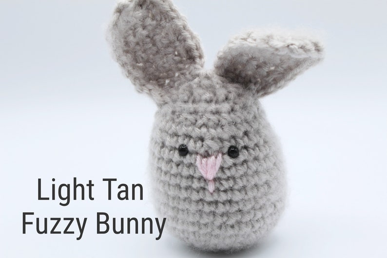 May include: A light tan fuzzy bunny crochet toy with black eyes and a pink nose.