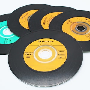 May include: A close-up of five blank, black CD-R discs with yellow and green labels. The labels feature the Verbatim brand name and specifications, including 700MB, 52x, and 80 min.
