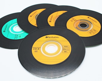 May include: A close-up of five blank, black CD-R discs with yellow and green labels. The labels feature the Verbatim brand name and specifications, including 700MB, 52x, and 80 min.