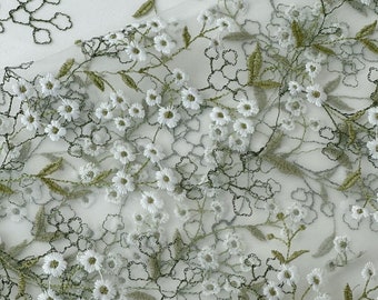 May include: White floral embroidery on a sheer green fabric. The flowers are small and delicate, with a simple design. The fabric is lightweight and airy, making it perfect for a variety of projects.