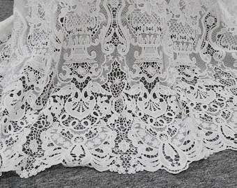 May include: White lace fabric with a delicate floral pattern. The lace has a scalloped edge and is made of a fine, lightweight material.
