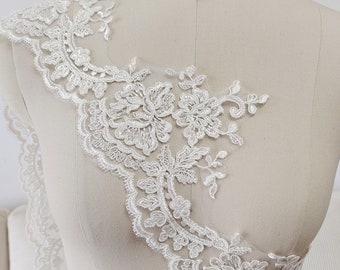 May include: White lace trim with a scalloped edge and floral designs. The lace is delicate and intricate, with a soft, flowing texture.