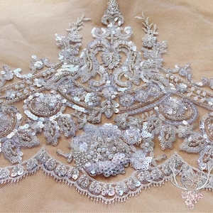 Pu&ograve; includere: Bordura di pizzo bianco con perline e paillettes con un motivo floreale. Il bordo &egrave; su un tessuto di rete trasparente.