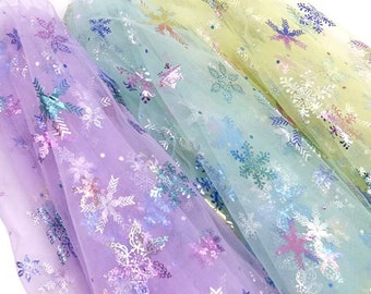 May include: Three layers of sheer fabric with a snowflake pattern. The fabric is iridescent and comes in shades of purple, green, and yellow.