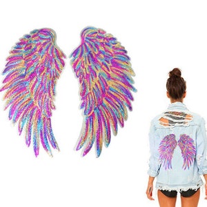 Op de afbeelding: Een paar regenboogkleurige engelenvleugels met roze, blauwe en gouden pailletten. De vleugels worden getoond op een spijkerjack met een distressed look.
