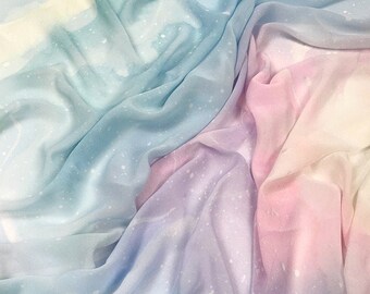 May include: A soft, sheer fabric with a gradient of light blue, pink, and white colors. The fabric has a subtle speckled pattern throughout.