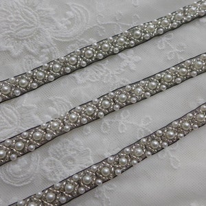 May include: Three rows of black ribbon trim with white pearl beads and silver accents.