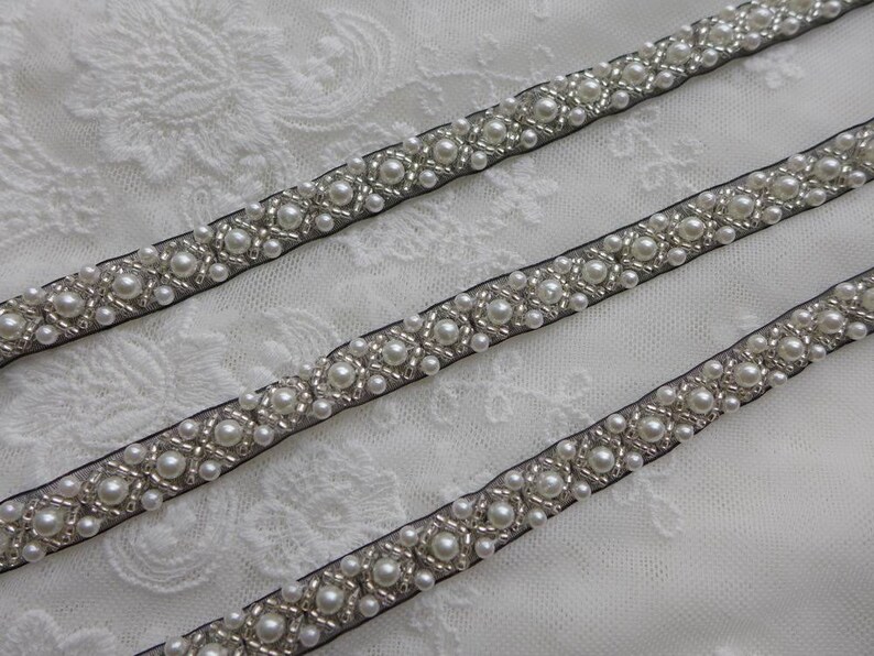 May include: Three rows of black ribbon trim with white pearl beads and silver accents.