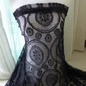 Peut inclure: Un v&ecirc;tement sans bretelles en dentelle noire pr&eacute;sentant un motif floral et circulaire pro&eacute;minent. Le design en maille complexe se compose d'anneaux interconnect&eacute;s et de motifs floraux stylis&eacute;s, cr&eacute;ant une texture semi-transparente.