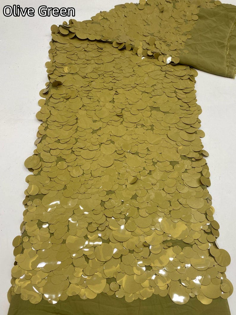 Puede incluir: Una pieza de tela verde oliva densamente cubierta con lentejuelas circulares superpuestas de varios tama&ntilde;os. El tejido presenta un esquema de color verde oliva monocrom&aacute;tico consistente, con el texto Olive Green en la esquina.