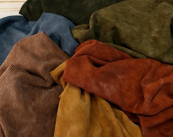 May include: A collection of corduroy fabric pieces in various colors including dark green, olive, blue, brown, mustard yellow, and burnt orange. Each piece features a distinct vertical ribbed texture characteristic of corduroy material.