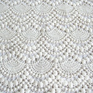 May include: White crocheted fabric with a delicate pattern of circles and loops. The fabric has a soft, airy texture.