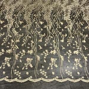 May include: Black mesh fabric with gold floral embroidery. The embroidery features delicate flowers and leaves, creating a flowing, elegant design.