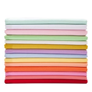 May include: A stack of folded fabric in various pastel colors, including mint green, white, pink, and yellow. The stack also includes shades of orange, red, and purple. The fabric appears to be soft and smooth, likely suitable for bedding or clothing.