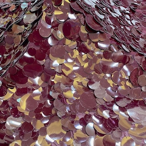 Puede incluir: Una superficie de tela densa cubierta de lentejuelas circulares superpuestas en un color burdeos intenso. Las lentejuelas var&iacute;an en tama&ntilde;o y presentan un acabado brillante y reflectante que crea luces y sombras en el material.