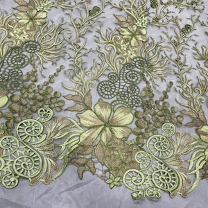 K&ouml;nnte beinhalten: Gr&uuml;ne und goldene florale Stickerei auf einem durchsichtigen Netzstoff. Das Design zeigt komplizierte Wirbel, Bl&auml;tter und Blumen.