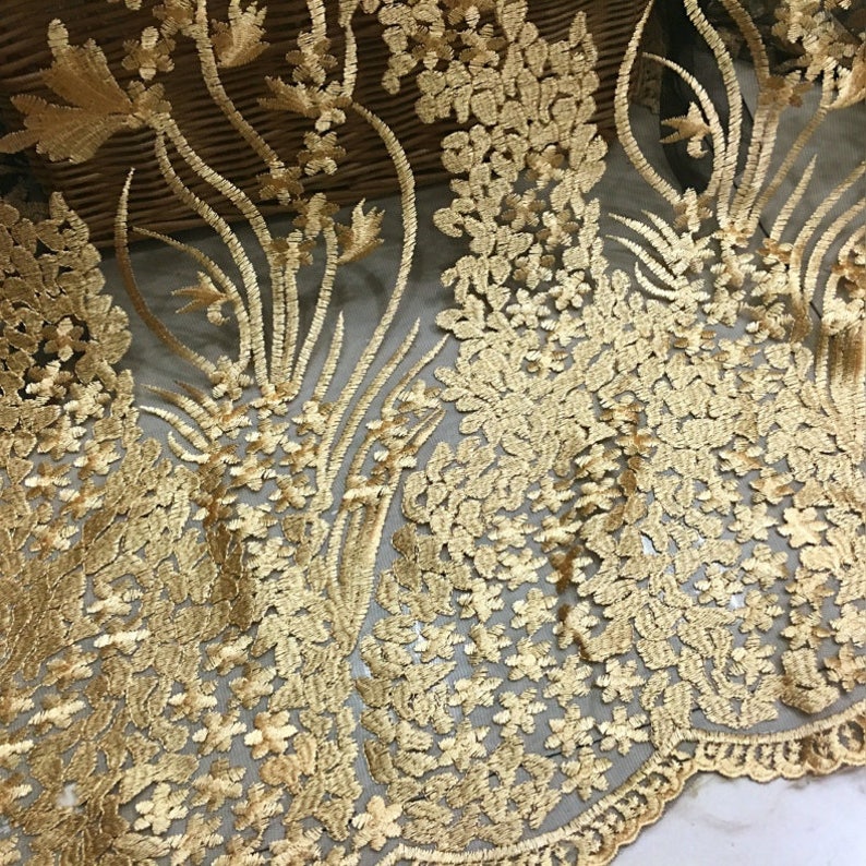 May include: Gold embroidered lace fabric with a floral pattern. The lace is delicate and intricate, with a sheer mesh background.