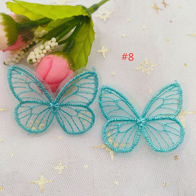 May include: Two turquoise blue butterfly shaped lace appliques with a gold glitter finish. #8