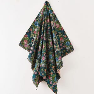 Puede incluir: Una pieza de tela rectangular con un fondo azul marino oscuro cubierto por un denso y colorido estampado floral. El dise&ntilde;o incluye varias flores en tonos rosa, rojo, azul claro y blanco, intercaladas con hojas y tallos de color verde.