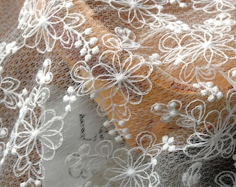 May include: White floral lace fabric with a delicate pattern. The lace is sheer and has a soft, flowing texture.