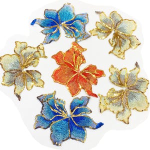 Op de afbeelding: Geborduurde bloemenapplicaties in blauwe, oranje en gouden tinten. De bloemvormige patches hebben ingewikkelde stiksels en pailletaccenten. Deze decoratieve applicaties zijn ideaal voor kleding of knutselprojecten.