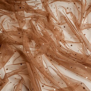 May include: Brown tulle fabric with gold glitter stars. The fabric is sheer and has a delicate texture.