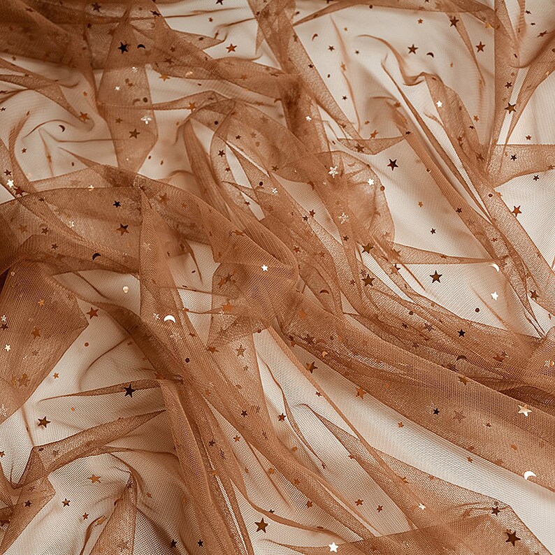 May include: Brown tulle fabric with gold glitter stars. The fabric is sheer and has a delicate texture.