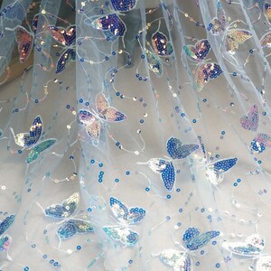 May include: Light blue tulle fabric with iridescent butterfly sequins. The fabric is sheer and has a delicate, feminine feel.
