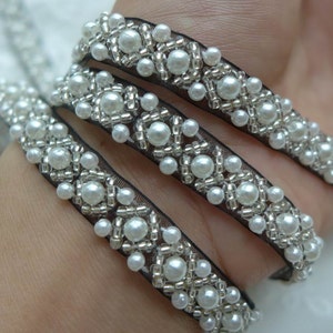 May include: White pearl trim with silver beads on black mesh ribbon.