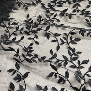 May include: Black embroidered leaf design on sheer fabric. The delicate leaves and vines create a repeating pattern across the textile. The fabric has a soft, flowing drape, suitable for various craft projects.