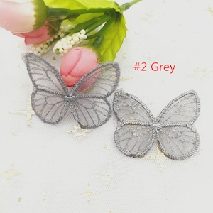 May include: Two grey lace butterfly appliques on a white background. #2 Grey.