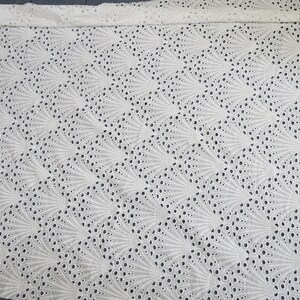 Puede incluir: Tela de algod&oacute;n blanca con un delicado y complejo patr&oacute;n de c&iacute;rculos y l&iacute;neas recortados, creando un dise&ntilde;o en forma de abanico.