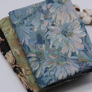 May include: Three folded pieces of woven fabric featuring floral patterns. The top layer displays large blue and white flowers. The middle layer shows green and brown foliage. The bottom layer features a black background with tan floral accents.