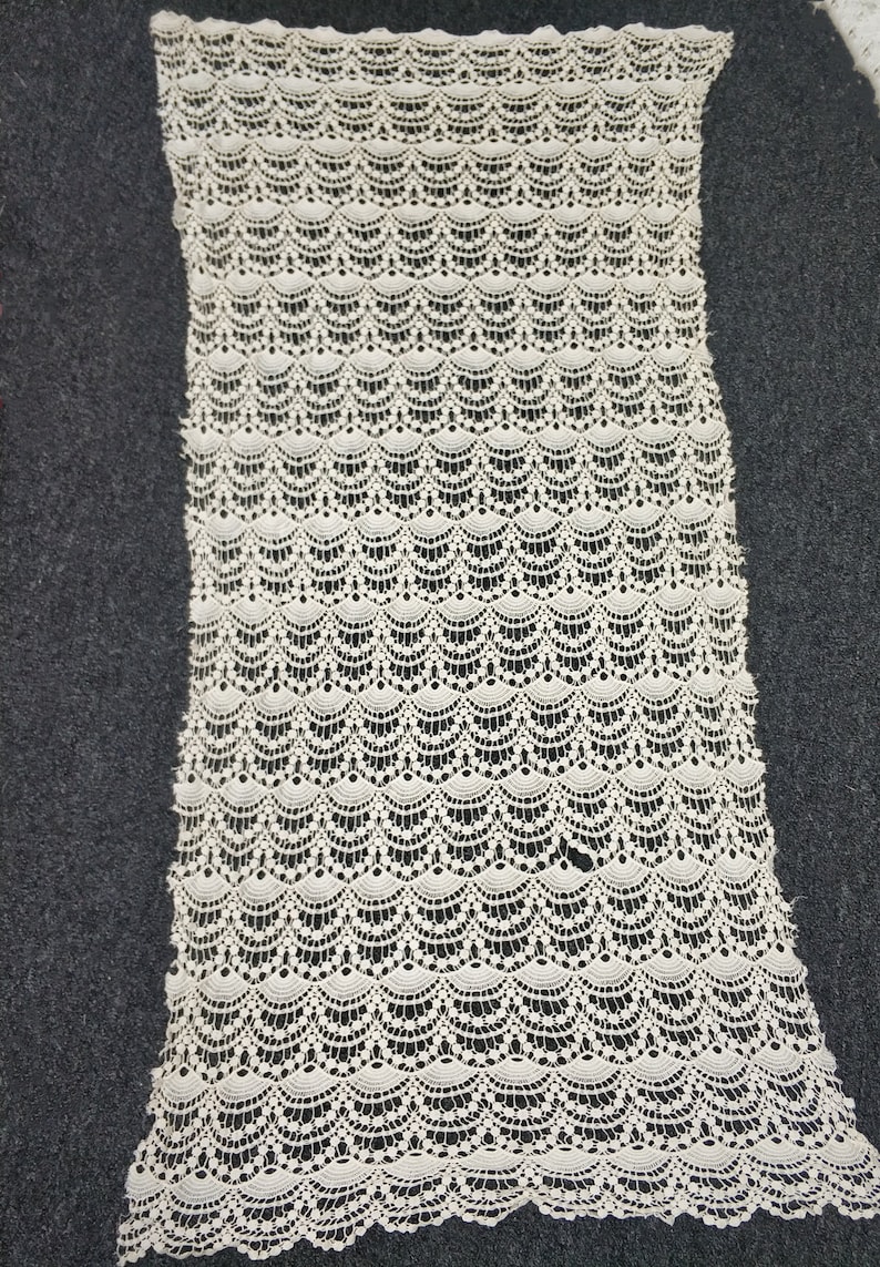 May include: White crocheted fabric with a scalloped pattern. The fabric is delicate and has a soft texture.