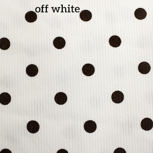 May include: An off-white fabric featuring a repeating pattern of dark brown polka dots. The material has a visible vertical ribbed texture throughout the surface. The text "off white" is printed in black in the upper left corner of the image.