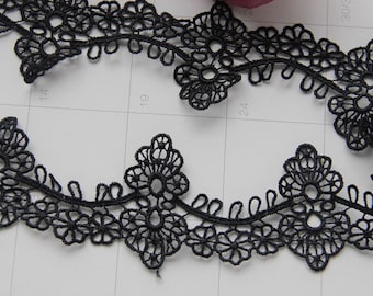 May include: Black lace trim with a floral design. The lace has a delicate, intricate pattern with small flowers and leaves.