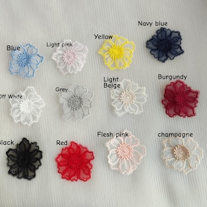 May include: A collection of twelve embroidered flower appliques in various colors including blue, light pink, yellow, navy blue, off white, grey, light beige, burgundy, black, red, flesh pink, and champagne, each labeled with its color name.