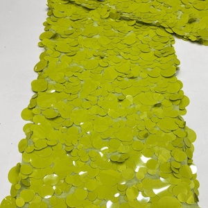 Puede incluir: Una tela de color verde brillante con una capa densa de lentejuelas circulares superpuestas. El texto "Bright Green" es visible en la esquina superior izquierda. Las lentejuelas son brillantes y redondas, cubriendo la base de malla verde claro.