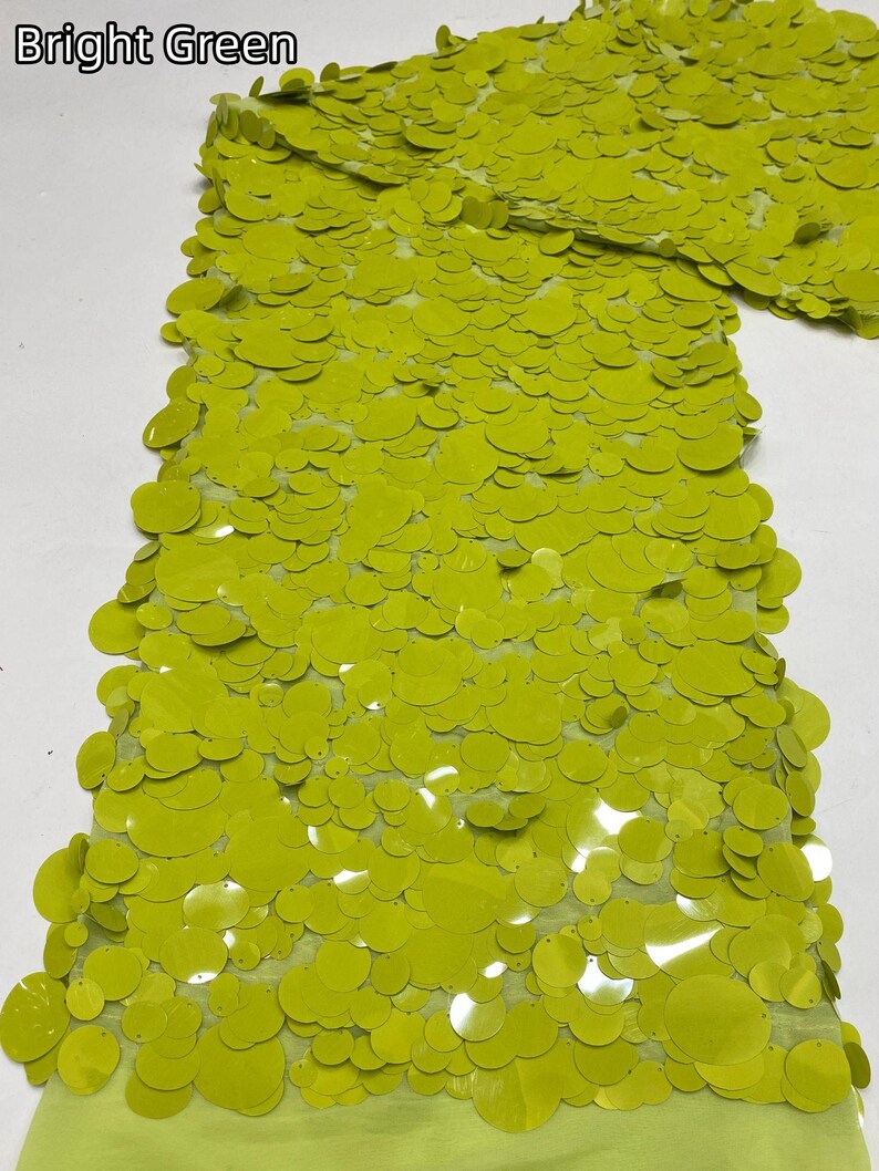 Puede incluir: Una tela de color verde brillante con una capa densa de lentejuelas circulares superpuestas. El texto "Bright Green" es visible en la esquina superior izquierda. Las lentejuelas son brillantes y redondas, cubriendo la base de malla verde claro.