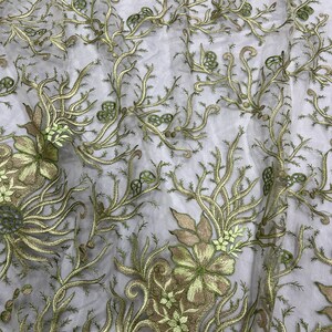 K&ouml;nnte beinhalten: Gr&uuml;ne florale Stickerei auf einem durchsichtigen wei&szlig;en Stoff. Das Design zeigt zarte Zweige und Blumen.