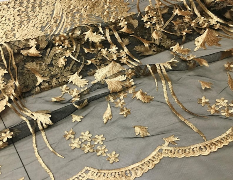 May include: Black mesh fabric with gold embroidery of floral and leaf designs. The fabric has a delicate, intricate pattern.