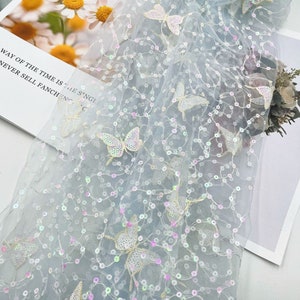 May include: Light blue tulle fabric with iridescent sequins and embroidered butterfly designs.