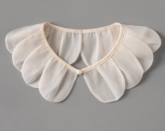 May include: A cream-colored, petal-shaped collar with a delicate, layered design. The collar is made of a sheer fabric and features a small pearl button closure at the front. The collar is a vintage-inspired accessory.