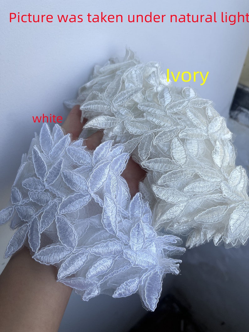 May include: Two swatches of lace fabric, one white and one ivory, with a leaf pattern. The fabric is delicate and has a soft, flowing texture.